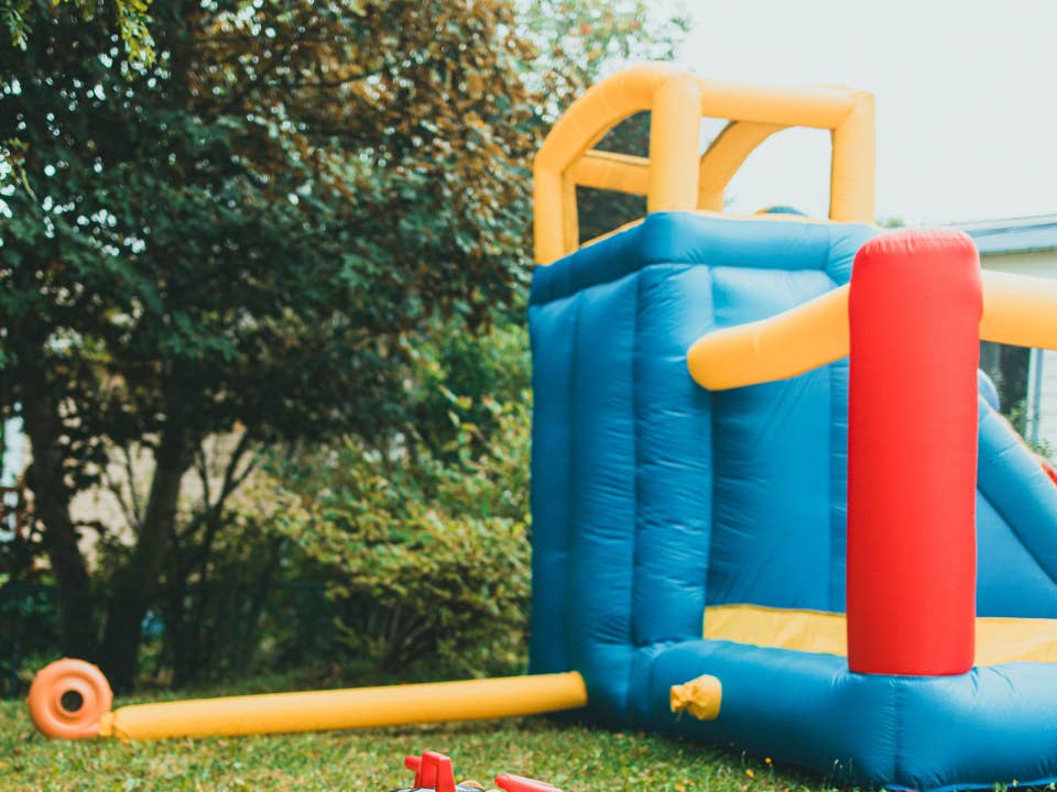Inflatable backyard play equipment anchored to a lawn